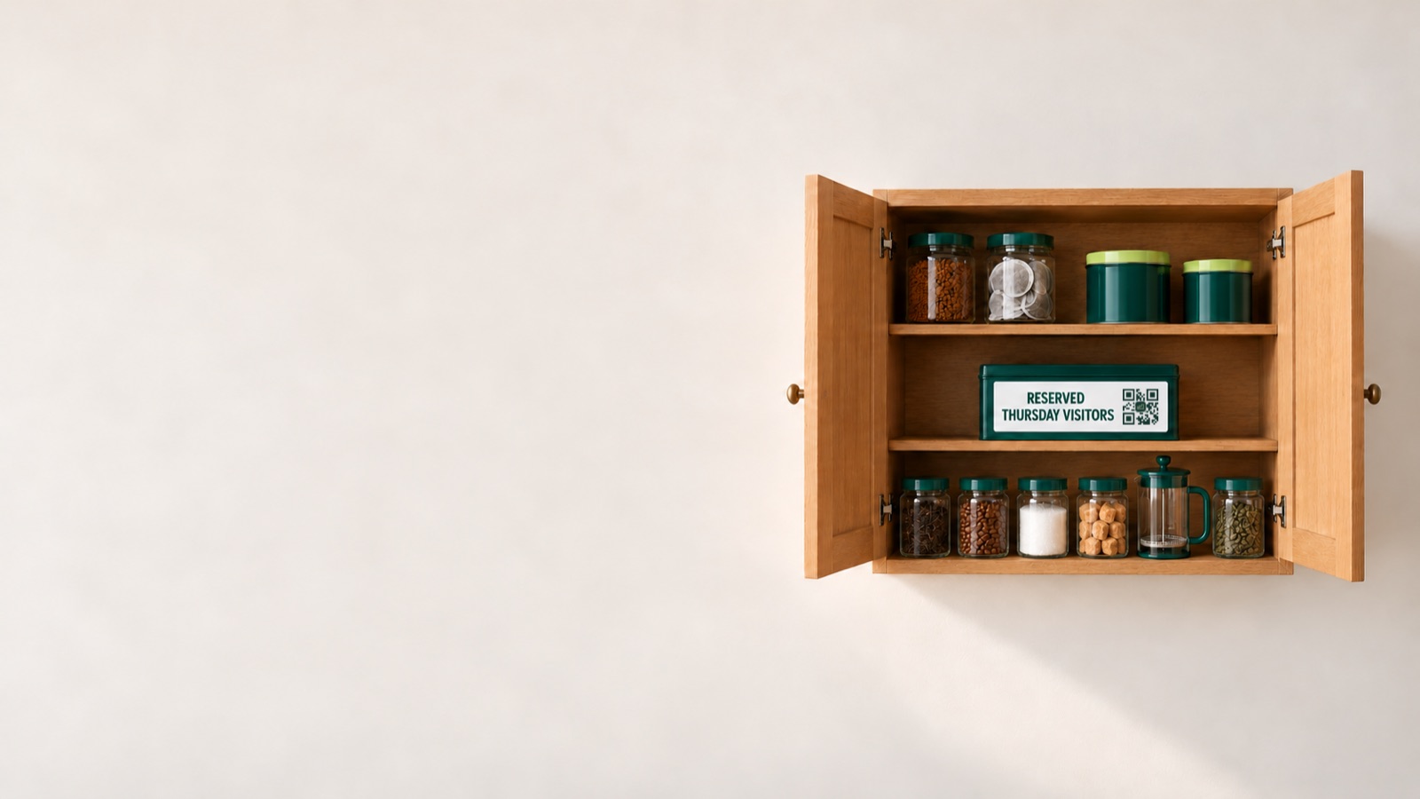 An open kitchen cupboard on a plain wall, with the reserved biscuit tin on the middle shelf.